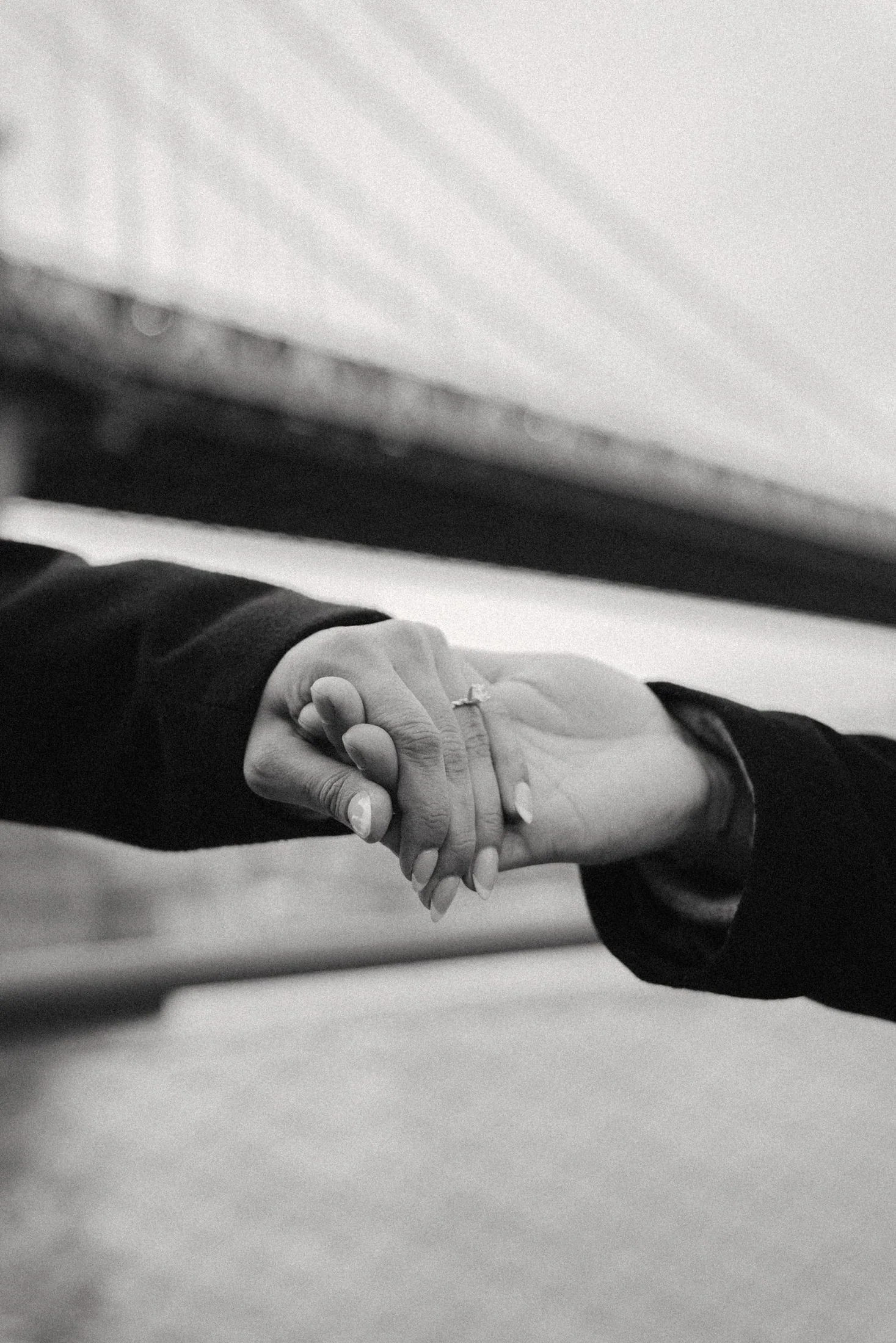Close black-and-white photograph of a couple holding hands