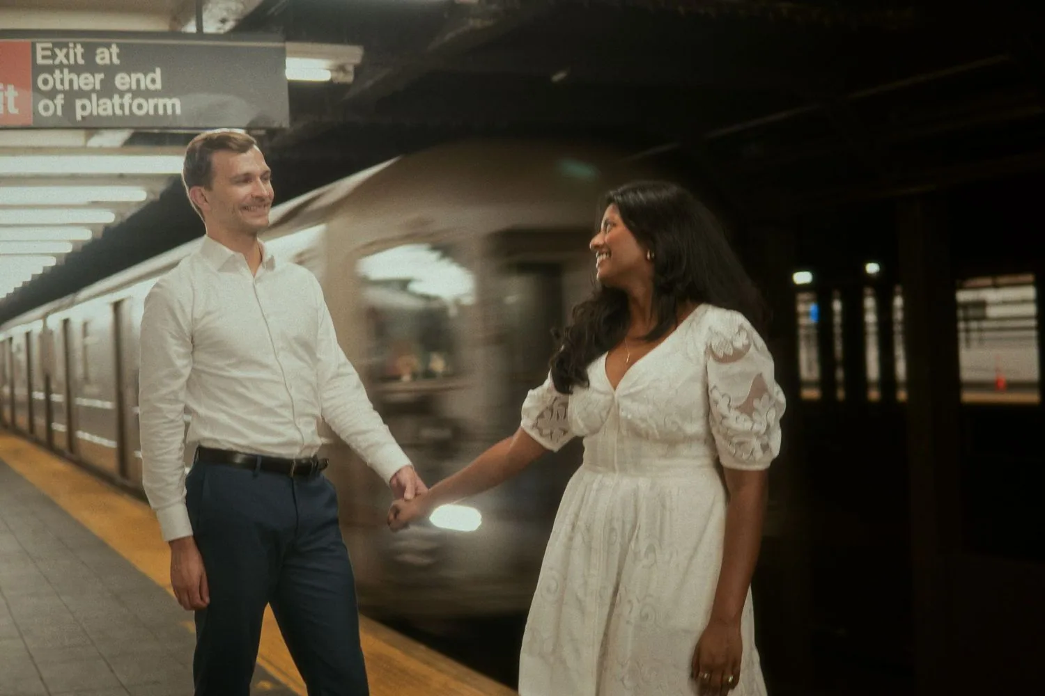 Engaged couple walking hand in hand on a New York subway platform