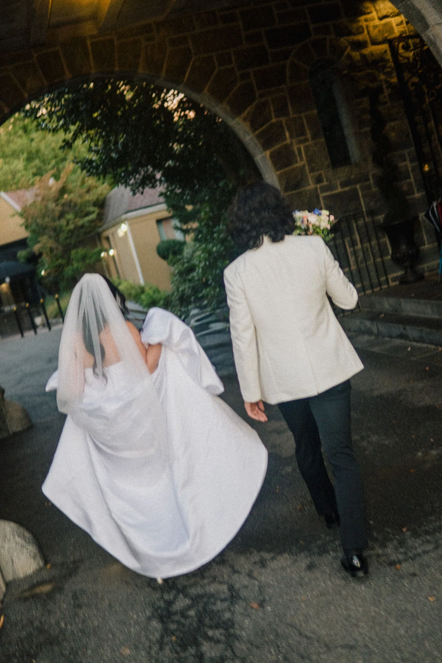 Newlyweds walking through a stone garden arch after their ceremony